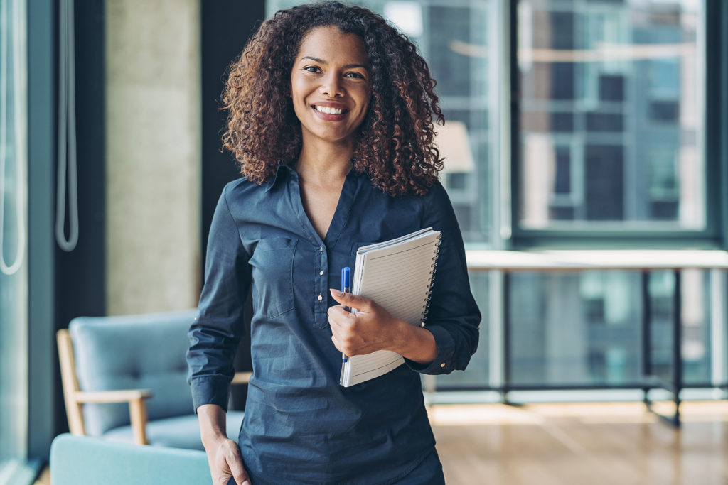 Real Estate Agent in Blue Dress Holding Book and Pen