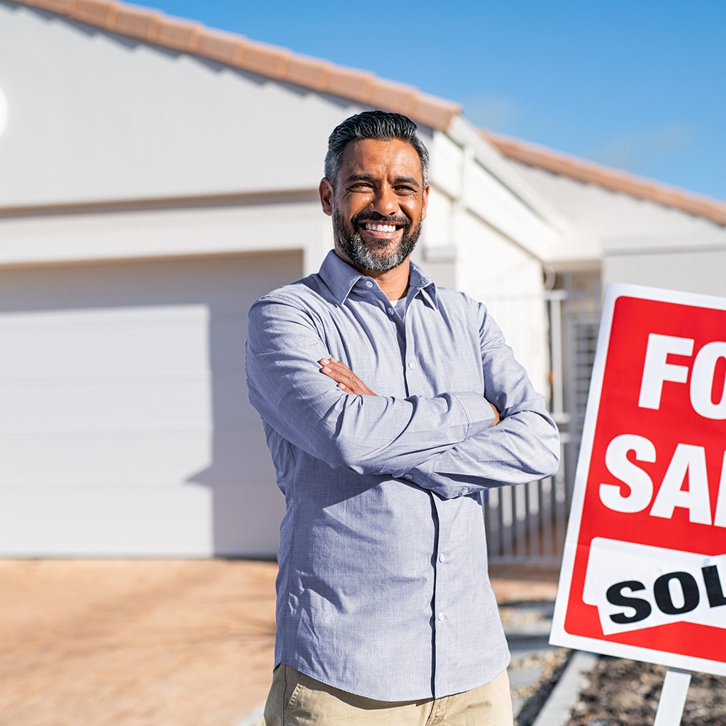 A man with folded hand standing outside house
