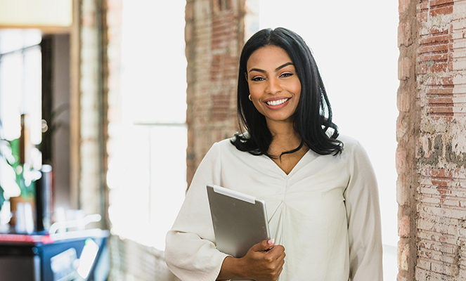 A woman holding a laptop and smiling